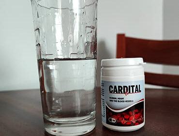 Баночка Cardital и стакан воды на столе.